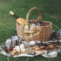 Picnic setting with two glasses of white wine, cheese, fruits and basket. Royalty Free Stock Photo