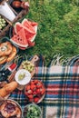 Picnic straw basket with healthy food, accessories. Summer picnic with cake, fruits, cheese, wine and snacks on plaid