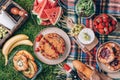 Picnic straw basket with healthy food, accessories. Summer picnic with cake, fruits, cheese, wine and snacks on plaid