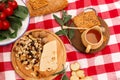 Picnic on the street on a checkered blanket spread out food. Honey and nuts on a wooden tray, next to bread, cheese, tomatoes and