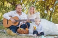 Picnic style outdoor wedding. Groom playing on guitar, young attractive blomde bride and little blond boy