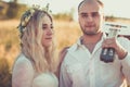 Picnic style outdoor wedding. Groom playing on guitar, young attractive blomde bride stand in summer sunset light