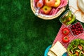 Picnic in summer with products, sandwich, salad, fruits, drink and hat on green grass texture background top view mockup