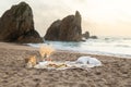 Picnic at sunset with wine, glasses, snacks and fruits on blanket, candles and decor on sand, beautiful view on ocean Royalty Free Stock Photo