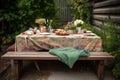 picnic table with a blanket, dishes, and silverware set out for an elegant outdoor meal Royalty Free Stock Photo