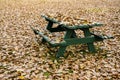 Picnic table hidden under golden autumn leaves Royalty Free Stock Photo