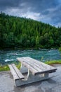 A picnic table beside a river flowing through a forest in Lapland  under the midnight sun, Norway Royalty Free Stock Photo