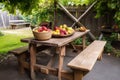 picnic table with a rustic, hand-carved bench and basket of fresh fruit