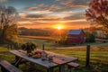A picnic table sits peacefully in a field, with a charming red barn as the backdrop, A beautiful sunset scene on a farm with a Royalty Free Stock Photo