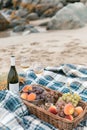 Picnic with wine and fruit in a wicker basket on a sandy beach by the sea. Royalty Free Stock Photo
