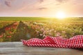 Picnic wooden table with checkered red napkin and roses on background