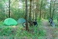Picnic in the woods. Two tents in the forest near a dirt path. Bicycle and motorcycle near the tent city in nature. Active leisure Royalty Free Stock Photo