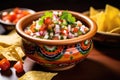pico de gallo in a vibrant ceramic bowl with chips nearby