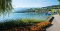 Pictorial lakeside promenade with colorful flower beds, view to lake Thunersee, Faulensee harbor and swiss alps