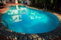 Closeup Oval Pool among Palm Trees in Hotel Yard