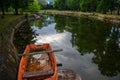 Panorama of an abandoned half sunken rowing boat, an orange small boat, resting in the neglected pond with muddy water