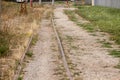 Perspective of old and rusty rail, meter gauge, on an abandoned railway line with its typical metal track covered in grass and mud Royalty Free Stock Photo