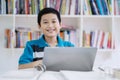 Asian preteen student using a laptop in the library Royalty Free Stock Photo