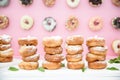 Picture of assorted donuts in a box with chocolate frosted, pink glazed and sprinkles donuts.