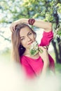 Picture of beautiful blonde young lady pretty girl with blue eyes standing under blooming tree & looking at camera Royalty Free Stock Photo