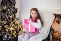 Picture of beautiful girl with gift boxes sitting on armchair at home. Decorated christmas tree background Royalty Free Stock Photo