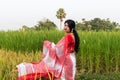 A picture of a Bengali girl wearing a red and white sari in a vast paddy field in autumn Royalty Free Stock Photo