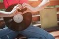 A picture of black vynil leaning to girl`s body. She is sitting on bench and crossing her legs. Girl is shwoing the love Royalty Free Stock Photo