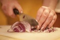 Women hands chopping red onions with a knife, on a white plank, with a speed blur and a focus on the onions, called allium sepa Royalty Free Stock Photo