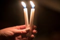 burning church candles in the hands of children on a dark background