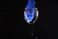 Picture of a burning glass cup set on fire with the help of medicinal alcohol, on a reflective surface