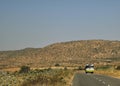 A Picture of a Bus travelling on an empty highway with Mountains