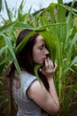 A sensual woman is standing in a field sheltering corn leaf close-up Royalty Free Stock Photo