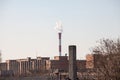 Industrial red chimney of a factory working and releasing toxic fume and smokes in the atmosphere in front of an industrial zone