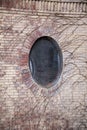 Circular window on the side of a brick building surrounded by ivy Royalty Free Stock Photo