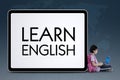 Clever schoolgirl sits near word of Learn English