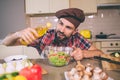 A picture of cook standing at table and holds bottle of sunflower oil. He looks at it and pouring some oil into bowl Royalty Free Stock Photo