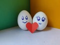 Picture of couple faces drawn on eggs with red heart and yellow and green background.