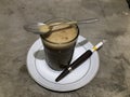 The Picture of a cup of coffee and a cigarette in a pipe