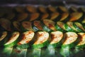 Picture of cut dark green zucchini covered with spices in process of baking