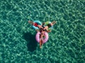 Picture with drone of people, floating on inflatable colorful rings in the sea