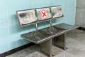 Picture of empty waiting chairs with social distancing sign, red cross mark. Metallic chair with social distancing symbol on seat