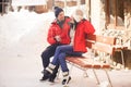 Picture of family couple in a winter clothes sitting on a wooden bench. Royalty Free Stock Photo