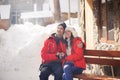 Picture of family couple in a winter clothes sitting on a wooden bench. Royalty Free Stock Photo