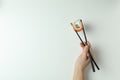 Female hand hold chopsticks with roll on white background Royalty Free Stock Photo