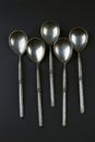 Five vintage silver teaspoons on black background