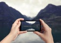 Picture of fjord in Norway on mobile phone. Female take picture of snow mountain on smart phone Royalty Free Stock Photo