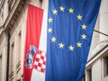 Croatian and European flags waiving in the air with a building in background. Croatia is the youngest country that joined the EU