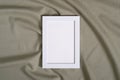 Picture frame with blank paper card mockup on green neutral colored textile