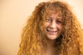 Picture of a funny joyful redhead pretty smiling woman looking at the camera over a golden background, copy space. Royalty Free Stock Photo