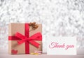 Picture of gift box with red ribbon and message thank you on greeting card, blur bokeh gray background. congratulation concept. Royalty Free Stock Photo